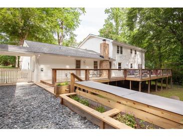 Expansive backyard view with large deck, stone path and flower beds in a lush, green setting at 5322 Seaton Dr, Atlanta, GA 30338