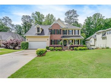 Traditional two-story home featuring brick and siding, black shutters, covered front porch, and a lush, green lawn at 1265 Kelly Nelson Dr, Lawrenceville, GA 30043