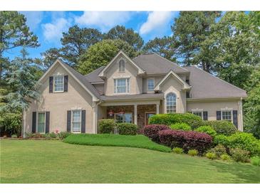 Charming stucco home with manicured lawn and colorful shrubs and decorative plants in a quiet suburban neighborhood at 1605 Little Lisa Ln, Snellville, GA 30078