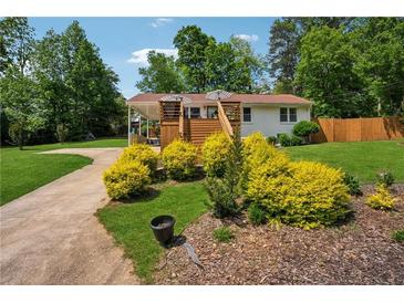Charming home featuring a spacious front yard, beautiful landscaping, and inviting deck, perfect for relaxing outdoors at 1932 Brenda Dr, Austell, GA 30168