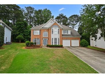 Traditional brick home with two-car garage and manicured lawn at 4325 Camellia Ridge Sw Way, Lilburn, GA 30047