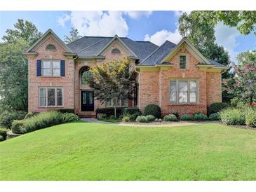 Elegant brick home featuring manicured lawn, mature trees, and a welcoming entrance at 2118 Town Manor Ct, Dacula, GA 30019