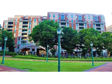 Landscaped exterior with a multi-story brick building with a gated entrance viewed from a green space at 250 Park Avenue West # 802, Atlanta, GA 30313