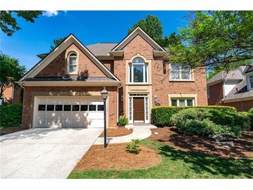 Charming two-story brick home featuring an attached garage and manicured landscaping at 4648 Glenshire Pl, Atlanta, GA 30338