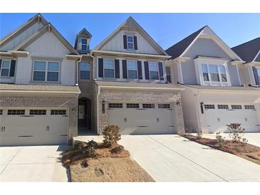 Charming townhome featuring brick accents, a two-car garage, and manicured landscaping at 2059 Lanier Harbor Pt, Buford, GA 30518