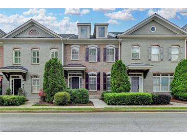 Charming townhome with manicured landscaping, stylish brick facade, and classic architectural details under a partly cloudy blue sky at 7435 Jamestown Dr, Alpharetta, GA 30005