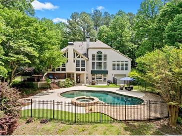 Backyard pool featuring a stone border, hot tub, and an elegant wrought iron fence at 8170 Hurakan Creek Xing, Cumming, GA 30028