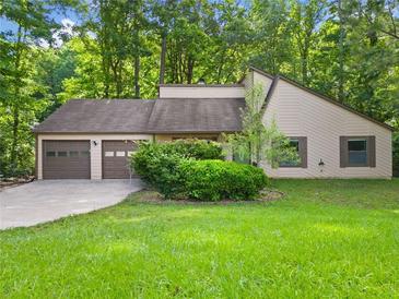Charming home featuring a two-car garage, well-maintained lawn, and beautiful landscaping and mature trees at 162 Riverchase Dr, Woodstock, GA 30188