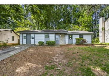 A single-story home with light siding, a stone accent, and a long driveway at 5445 Mallard Trl, Lithonia, GA 30058