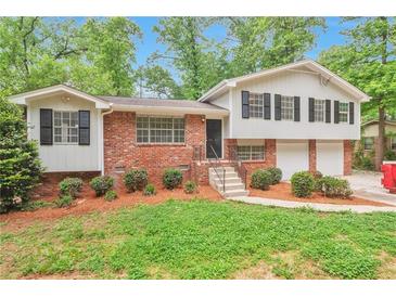 Charming brick home featuring black shutters, a well-manicured lawn, and a two-car garage at 5911 Christopher Ln, Lithonia, GA 30058