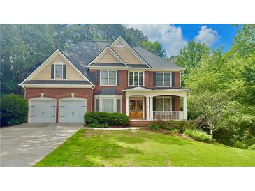 Charming two-story brick home featuring an attached two-car garage, covered porch and a well manicured lawn at 3744 Heathermoor Ct, Dacula, GA 30019