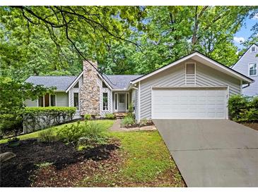 Charming home featuring a stone chimney, well-manicured lawn, and attached two-car garage at 413 Sassafras Rd, Roswell, GA 30076