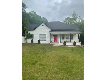 Attractive home featuring a classic front porch, neat landscaping, and a vibrant red door at 6860 Parkway Dr, Lithonia, GA 30058