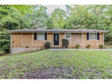 Charming single story home featuring a well-kept lawn, trimmed shrubs, and a unique stone facade at 5509 Covent Way, Lithonia, GA 30058