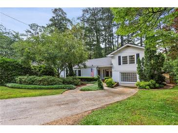 Inviting two-story home featuring manicured landscaping, a well-kept lawn, and a quaint front-facing garage at 88 Karland Nw Dr, Atlanta, GA 30305
