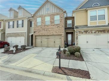 Charming townhome with a two-car garage, manicured landscaping, and a welcoming front entrance at 3318 Sardis Bend Dr, Buford, GA 30519