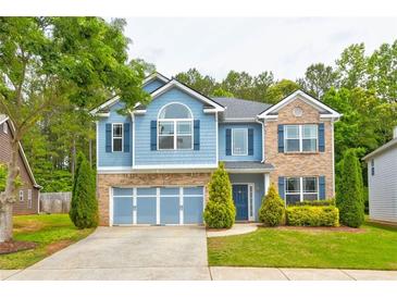 Charming two-story home with a blue exterior, brick accents, a well-manicured lawn, and a two-car garage at 133 Parkway Dr, Fairburn, GA 30213