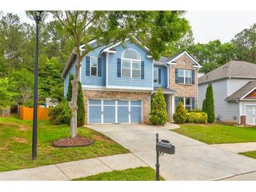 Charming two-story home boasts a well-manicured lawn, blue siding, and a two-car garage at 133 Parkway Dr, Fairburn, GA 30213
