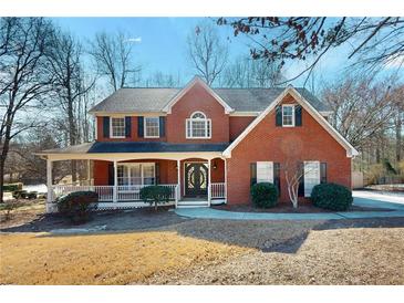 Charming two-story red brick home with a covered front porch and well-manicured landscaping on a sunny day at 2995 Aspen Ridge Ct, Snellville, GA 30078