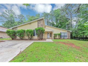 Charming home with a well-maintained lawn, complemented by lush greenery and trees at 6350 Mozart Dr, Riverdale, GA 30296