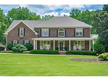 Charming brick home featuring a covered porch, manicured landscaping, and lush green lawn at 210 Little River Farms Trl, Canton, GA 30115