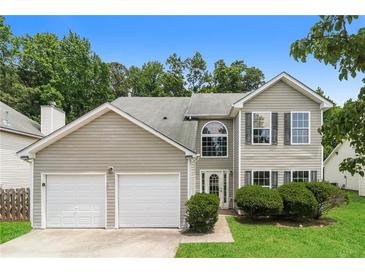 Charming two-story home with a two-car garage, green lawn, and manicured bushes at 2743 High Tide Dr, Atlanta, GA 30349
