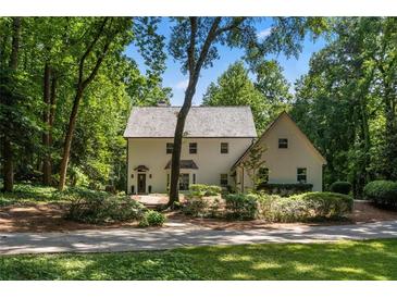 Inviting two-story home featuring a light-colored exterior, mature trees and a charming landscaped yard at 1260 Heards Ferry Rd, Sandy Springs, GA 30328