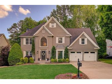 Charming two-story home featuring a well-manicured lawn, symmetrical landscaping, and a two-car garage at 5028 Winding Hills Ln, Woodstock, GA 30189