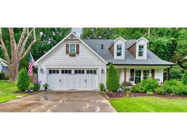 Charming two-story home with a white exterior, a 2-car garage, a manicured lawn, and an American flag at 115 Ocee View Ct, Alpharetta, GA 30022