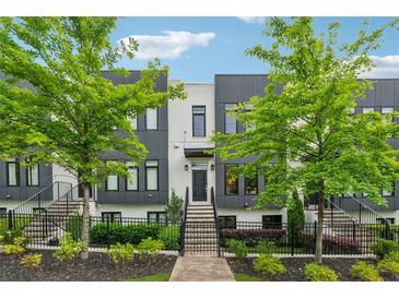 Modern two-story townhome with a black fence, landscaped yard, and stairs leading to the front door at 1106 Briar Cove Cir, Atlanta, GA 30329