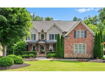 Charming two-story home featuring a brick facade, landscaped lawn, and mature trees on a sunny day at 5025 Savannah Run, Cumming, GA 30040
