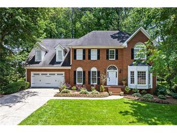 Stately brick home with lush front lawn, two car garage, and professionally landscaped flower beds at 763 Old Paper Mill Se Dr, Marietta, GA 30067
