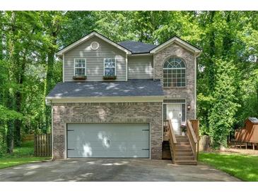 Charming two-story home features a brick facade, arched window, and a two-car garage nestled among mature trees at 2766 Stonecreek Se Rd, Smyrna, GA 30080