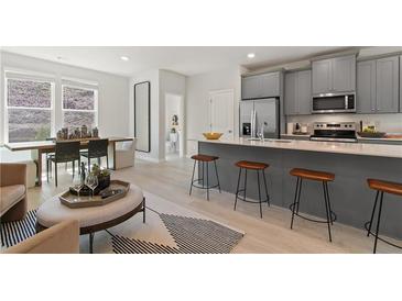 Open-concept kitchen featuring stainless steel appliances, gray cabinetry, and a central island with bar stool seating at 3142 Washburn St, Atlanta, GA 30354