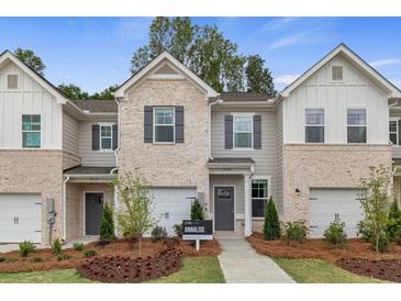 Charming townhome exterior with brick accents, gray siding, and well-manicured landscaping at 324 Navigator Ln, Mcdonough, GA 30253