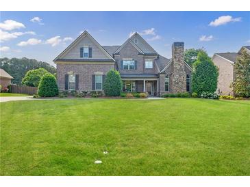 Charming two-story brick home with a stone chimney and a beautifully landscaped front yard at 468 Scott Farm Dr, Powder Springs, GA 30127