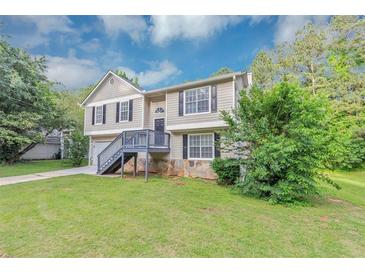 Charming two-story home with a stone foundation, gray siding and mature trees at 5290 Forest Downs Ln, Atlanta, GA 30349
