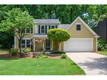 Charming home features a manicured lawn, mature trees, and a two-car garage at 9050 Brockham Way, Alpharetta, GA 30022