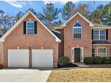 Charming two-story red brick home featuring an attached two car garage and a manicured front lawn at 6322 Shell Sw Dr, Atlanta, GA 30331