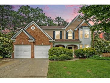 Charming two-story home featuring a manicured lawn, brick accents, and a convenient two-car garage at 2717 High Creek Run, Dacula, GA 30019