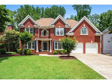 Charming two-story brick home with a manicured lawn, mature trees, and an attached two-car garage at 3944 Blustery Ne Way, Marietta, GA 30066