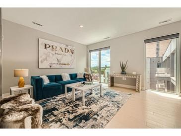 Bright living room featuring a plush blue sofa, modern art, and an open floor plan with large windows at 775 Juniper Ne St # 612, Atlanta, GA 30308