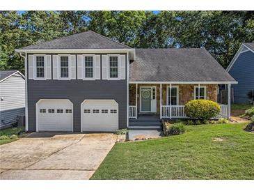 Charming two-story home featuring a stone facade, gray siding, shutters, a well-manicured lawn, and a two-car garage at 4865 Fenbrook Dr, Stone Mountain, GA 30088