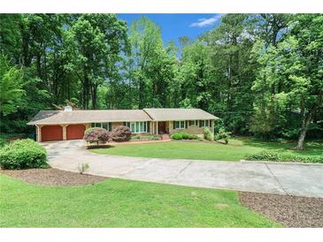 Charming home boasts a lush, green lawn and a circular driveway surrounded by mature trees at 5170 Oxbow Rd, Stone Mountain, GA 30087