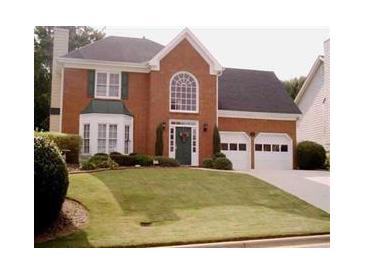 Charming two-story brick home featuring a well-manicured lawn, arched window and two-car garage at 1414 Justin Dr, Lawrenceville, GA 30043