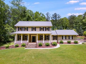 Charming two-story home with a covered front porch and well-manicured lawn, surrounded by lush trees at 7720 Milam Rd, Winston, GA 30187