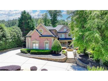 Stunning brick home featuring lush landscaping, fountain, and a circular driveway at 8525 Saint Marlo Fairway Way, Duluth, GA 30097