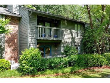 Two-story condo with brick accents and a covered balcony overlooking lush landscaping at 1205 Mcclelen Way, Decatur, GA 30033
