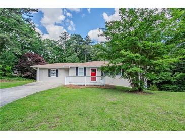 Charming single-story home featuring a well-manicured lawn, a red door, and a cozy front porch at 3920 Stonewall Tell Rd, Atlanta, GA 30349