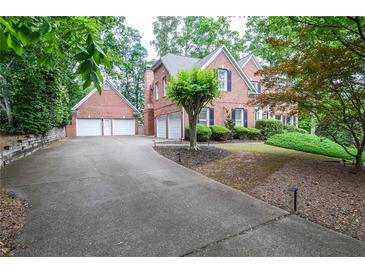 Brick two-story home featuring a three-car garage, a brick detached two-car garage, and driveway at 6450 Oak Valley Dr, Cumming, GA 30040